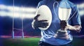Composite image of mid section of sportsman holding trophy and rugby ball