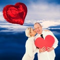 Composite image of older affectionate couple holding red heart shape Royalty Free Stock Photo