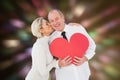 Composite image of older affectionate couple holding red heart shape Royalty Free Stock Photo