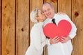 Composite image of older affectionate couple holding red heart shape Royalty Free Stock Photo