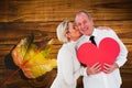 Composite image of older affectionate couple holding red heart shape Royalty Free Stock Photo