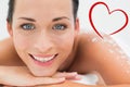 Composite image of peaceful brunette lying with salt scrub on back smiling at camera Royalty Free Stock Photo