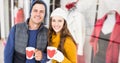 Composite image of portrait of caucasian couple holding mugs smiling against boutique in background Royalty Free Stock Photo