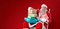 Composite image of portrait of cheerful santa claus holding christmas presents on chair Royalty Free Stock Photo