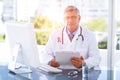 Composite image of portrait of confident male doctor sitting at computer desk Royalty Free Stock Photo