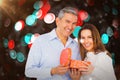 Composite image of portrait of happy couple opening present Royalty Free Stock Photo