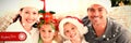 Composite image of portrait of a happy family with christmas hats sitting on the sofa Royalty Free Stock Photo