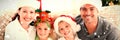 Composite image of portrait of a happy family with christmas hats sitting on the sofa Royalty Free Stock Photo