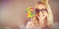 Composite image of portrait of a hipster with a party hat holding a lollipop Royalty Free Stock Photo