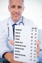 Composite image of portrait of a male doctor showing a blank prescription sheet Royalty Free Stock Photo