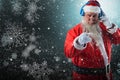 Composite image of portrait of santa claus listening to music on headphones while pointing Royalty Free Stock Photo