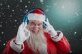 Composite image of portrait of santa claus showing hand okay sign while listening to music on headph Royalty Free Stock Photo