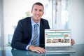 Composite image of portrait of smiling businessman showing laptop Royalty Free Stock Photo