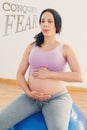 A Composite image of pregnant brunette sitting on exercise ball breathing