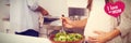 Composite image of pregnant woman mixing a salad in the kitchen