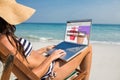 Composite image of pretty brunette using laptop on deck chair Royalty Free Stock Photo