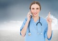 Composite image of pretty woman doctor phoning and pointing with her finger Royalty Free Stock Photo