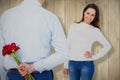 Composite image of rear view of man hiding roses behind back from woman Royalty Free Stock Photo