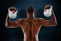 Composite image of rear view of shirtless fit man lifting kettle bells