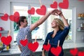 Composite image of red hanging hearts and couple dancing in the kitchen Royalty Free Stock Photo