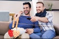 Composite image of red hanging hearts and friends watching tv in living room Royalty Free Stock Photo