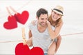 Composite image of red hanging hearts and man giving piggyback to woman Royalty Free Stock Photo