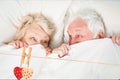 Composite image of red hanging hearts and senior couple relaxing on bed Royalty Free Stock Photo