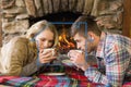 Composite image of romantic couple drinking tea in front of lit fireplace