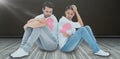 Composite image of sad couple sitting holding two halves of broken heart Royalty Free Stock Photo