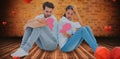 Composite image of sad couple sitting holding two halves of broken heart Royalty Free Stock Photo