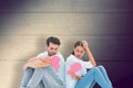 Composite image of sad couple sitting holding two halves of broken heart Royalty Free Stock Photo