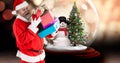 Composite image of santa claus carrying christmas gifts with snow globe in background Royalty Free Stock Photo