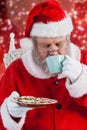 Composite image of santa claus drinking coffee with cookies Royalty Free Stock Photo