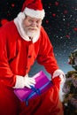 Composite image of santa claus putting christmas presents in christmas bag Royalty Free Stock Photo