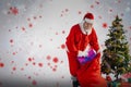 Composite image of santa claus putting presents in bag by christmas tree Royalty Free Stock Photo