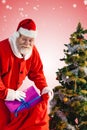 Composite image of santa claus putting presents in bag by christmas tree Royalty Free Stock Photo