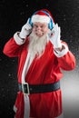 Composite image of santa claus showing hand okay sign while listening to music on headphones Royalty Free Stock Photo