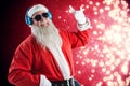 Composite image of santa claus showing hand sign while listening to music on headphones Royalty Free Stock Photo