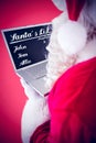 Composite image of santa claus using his laptop Royalty Free Stock Photo