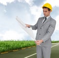 Composite image of serious architect with hard hat looking at plans Royalty Free Stock Photo