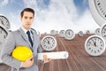 Composite image of serious architect holding plans and hard hat Royalty Free Stock Photo