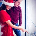 Composite image of side view of couple in christmas attire looking at wrist watch display Royalty Free Stock Photo