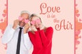 Composite image of silly couple holding hearts over their eyes Royalty Free Stock Photo