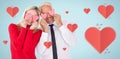 Composite image of silly couple holding hearts over their eyes Royalty Free Stock Photo