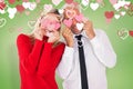 Composite image of silly couple holding hearts over their eyes Royalty Free Stock Photo