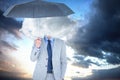 Composite image of smiling businessman looking at camera under umbrella Royalty Free Stock Photo