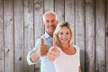 Composite image of smiling couple showing thumbs up together Royalty Free Stock Photo