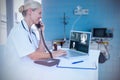 Composite image of smiling doctor using laptop while talking on telephone Royalty Free Stock Photo