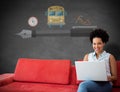Composite image of smiling female college student using laptop while sitting on sofa Royalty Free Stock Photo