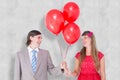 A Composite image of smiling geeky couple holding red balloons